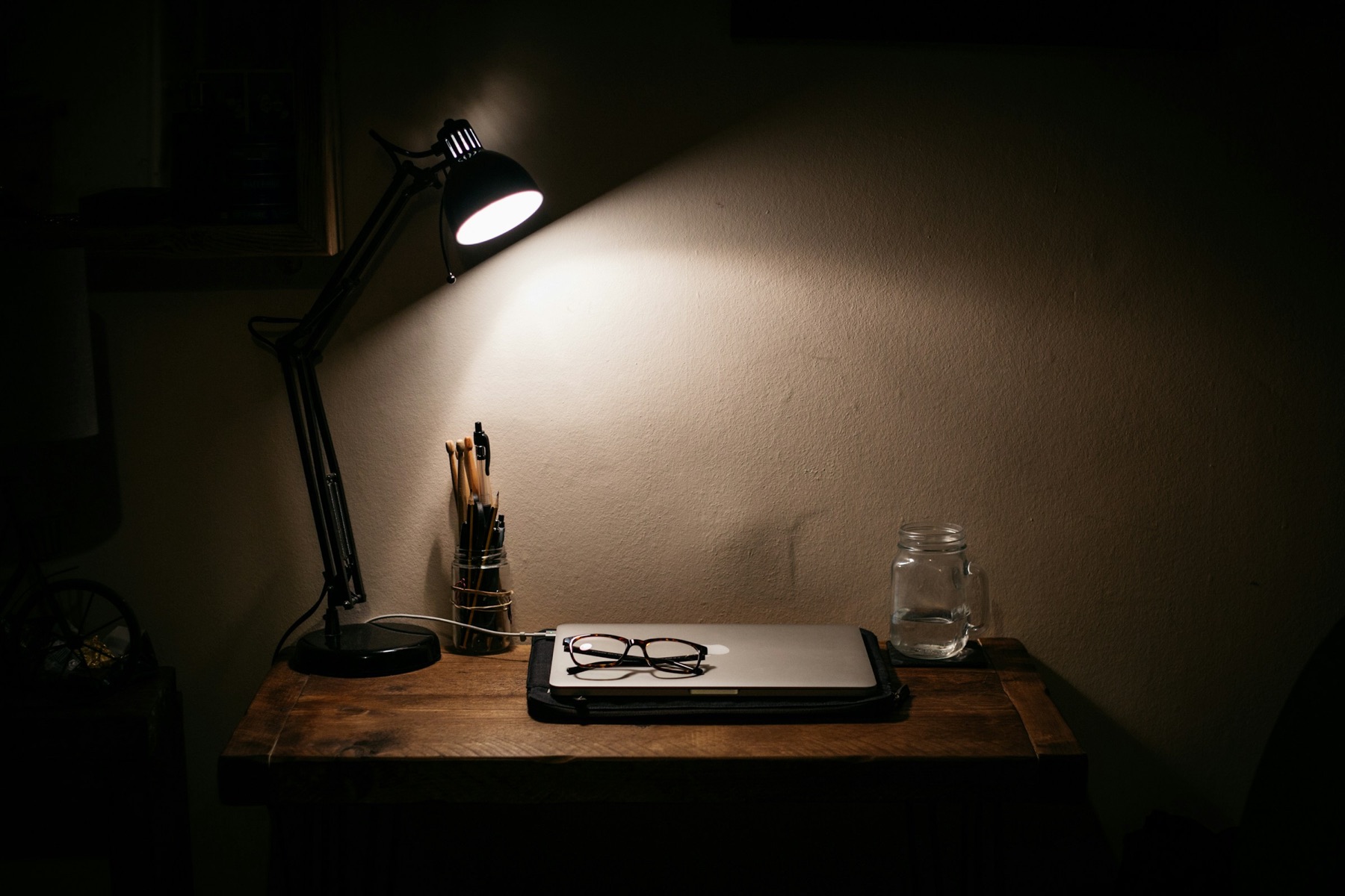 A desk lamp over a closed laptop, late in the evening